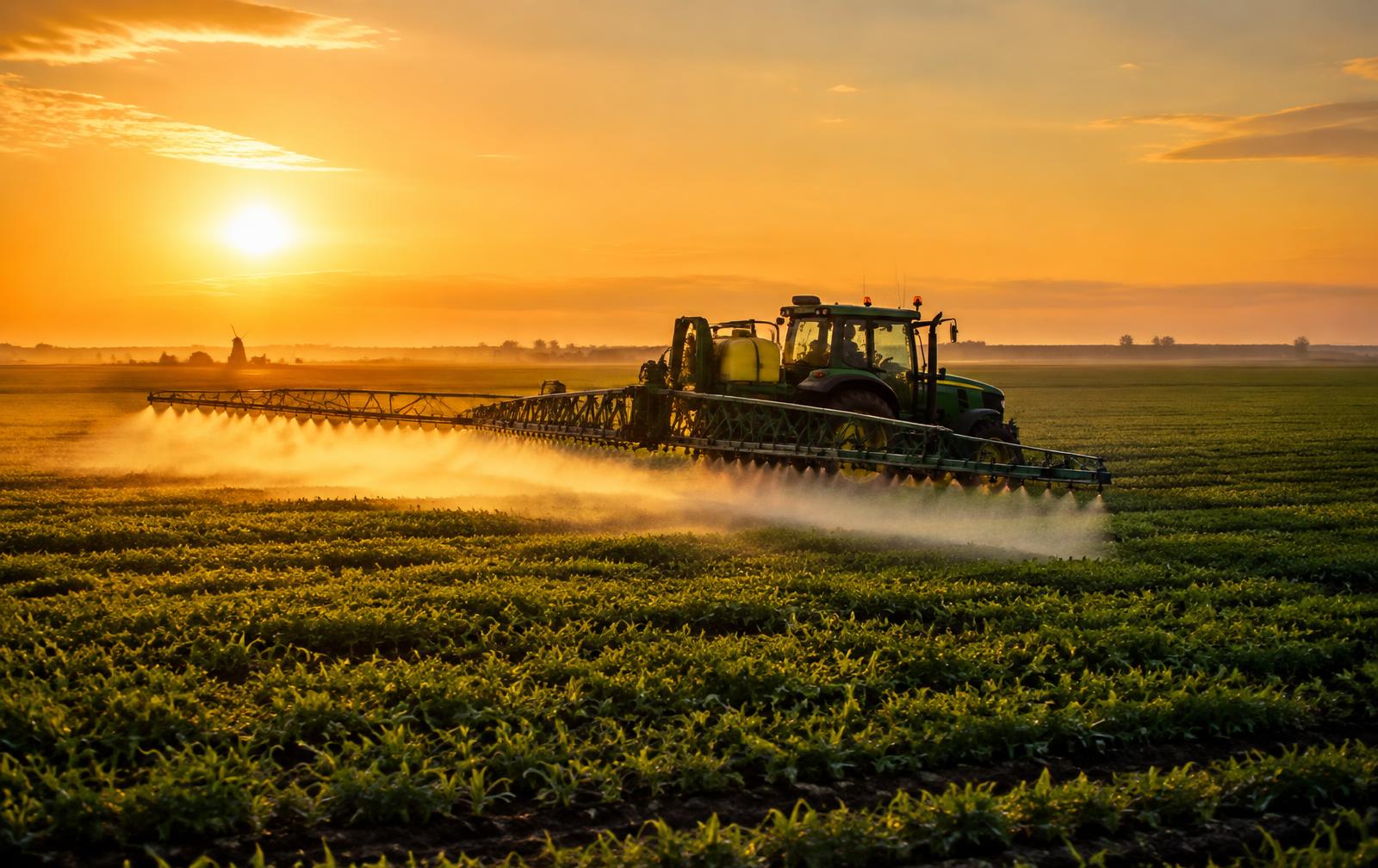 Veldspuit aan het werk bij zonsondergang